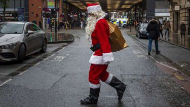 En man utklädd till jultomte går genom Manchesters centrum