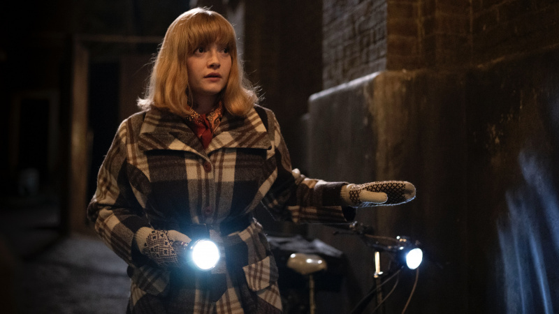   Natalie Quarry tšekkmantlis Rosalindina hoiab käes tõrvikut, kui ta kõnnib mööda tänavat 2024. aasta jõulude eriprogrammis Call the Midwife.