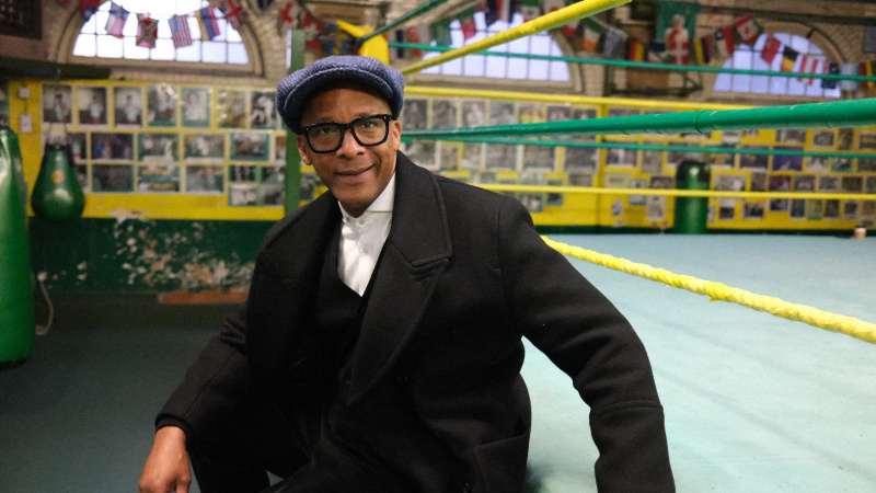   Jay Blades นั่งอยู่บนขอบเวทีมวยใน Jay Blades: East End Through Time