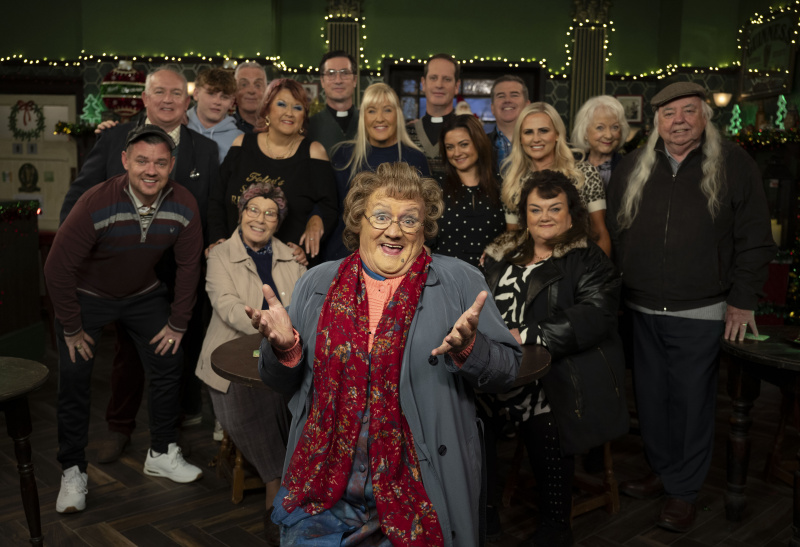   Актьорският състав на мисис Браун's Boys in character, with Mrs Brown at the front and everyone smiling behind her.