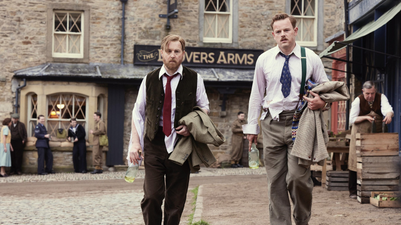  Samuel West v košeli a veste vyzerá strapato a drží fľašu ako Siegfried a Callum Woodhouse v košeli so sakom ako Tristan vo filme All Creatures Great and Small.