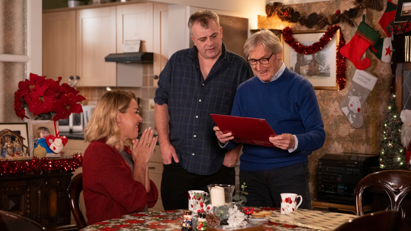  Ken Barlow avaa lahjan, kun Cassie Plummer ja Steve Barlow katsovat häntä Coronation Streetillä.