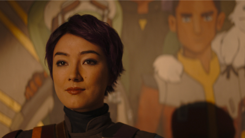   O Sabine Wren cu părul scurt care stă în fața picturii murale a lui Ezra Bridger din episodul 2 Ahsoka