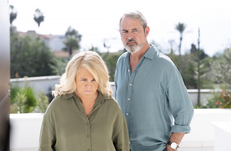   Sally Lindsay vihreässä topissa Emmana ja Neil Morrissey sinisessä paidassa Peten seisoessa oven ulkopuolella auringossa Love Ratissa.