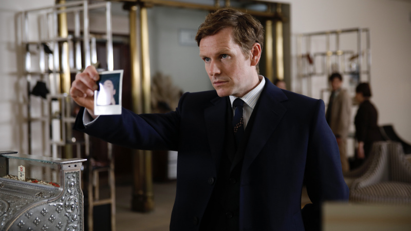   Shaun Evans v tmavom obleku ako Endeavour drží fotku v Endeavour.