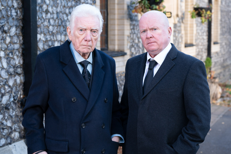  Stevie Mitchell en Phil Mitchell dragen zwarte pakken buiten een kerk.