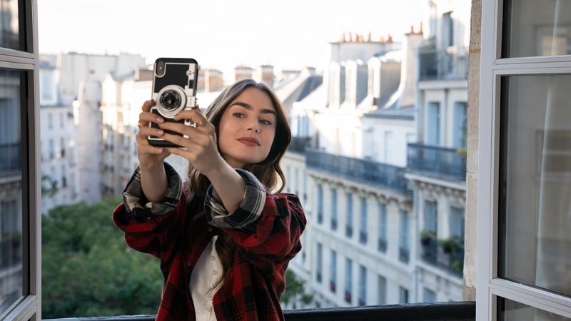 Emily la Paris ține în mână un iPhone făcând un selfie
