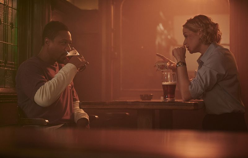 Baz (Nathaniel Martello-White) in Sadie (Niamh Algar) skupaj sedita v pubu, pijeta in se igrata s krovom kart