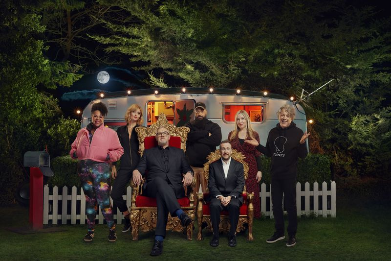 Serialo 12 „Taskmaster“ dalyvių, esančių už „Taskmaster“ karavano, grupė: Desiree Burch, Morgana Robinson, Guz Khan, Victoria Coren Mitchell ir Alanas Daviesas. Gregas Daviesas ir Alexas Horne