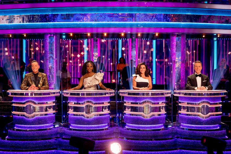 Οι δικαστές Craig Revel Horwood, Motsi Mabuse, Shirley Ballas και Anton Du Beke κάθονται πίσω από τα ατομικά τους θρανία (χωρισμένα με διαφανείς οθόνες) στο στούντιο Strictly