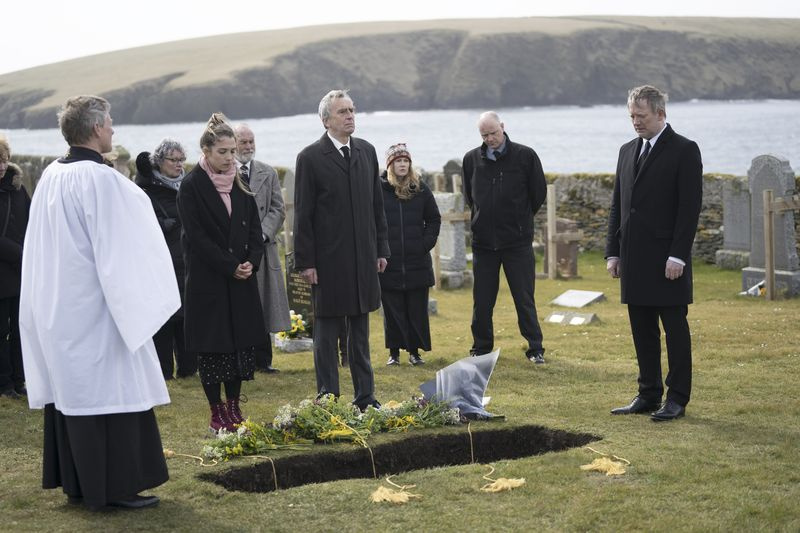 Η Cassie (Erin Armstrong), ο James (Benny Young) και ο Perez (Douglas Henshall) στέκονται δίπλα σε έναν ανοιχτό τάφο και δείχνουν έρημοι κατά τη διάρκεια της κηδείας του Perez