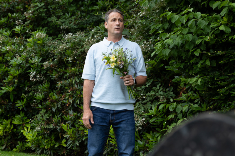   Tony Hutchinson อยู่ที่สุสานโดยถือช่อดอกไม้
