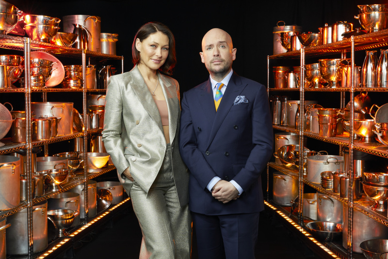  Η Emma Willis και ο Tom Allen στέκονται ανάμεσα σε δύο ράφια εξοπλισμού μαγειρικής