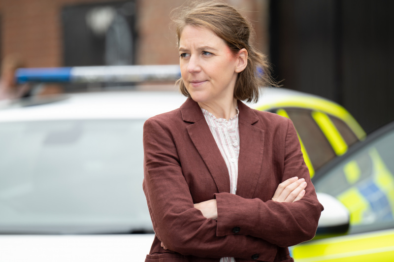   Sarah Collins มีรอยช้ำบนใบหน้าขณะกอดอกต่อหน้ารถตำรวจ