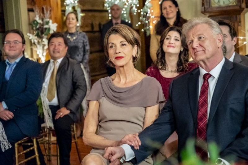 When Miranda Chester set off to find information on her biological father two Christmases ago, she never imagined that her investigation would lead her to both the family she had always longed for and Ian McAndrick the love of her life. After her romantic engagement last Christmas, Miranda prepares to marry Ian surrounded by his family, and her new family, the Whitcombs. Her plans are quickly complicated when a mysterious visitor who claims to have ties to her late parents reaches out to her just days before her wedding. While Miranda navigates this new relationship, her late fathers widow, Margaret, forges a surprising romance with a friend from the past. Photo: Wendie Malick Credit: 2018 Crown Media United States LLC/Photographer: Kailey Schwerman