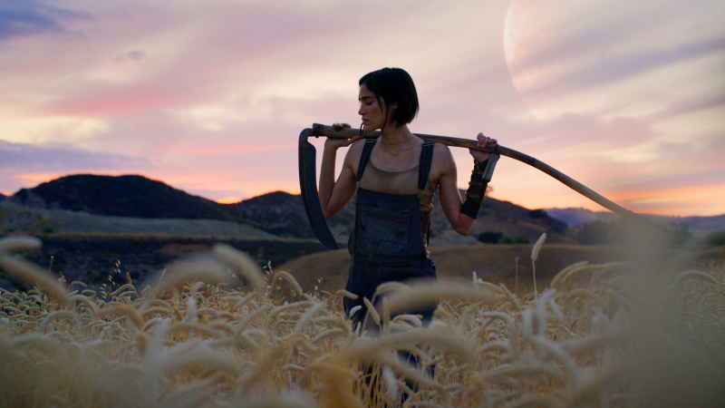   Kora (Sofia Boutella), Rebel Moon - Birinci Bölüm: Ateşin Çocuğu'nda bir tarlada orakla poz veriyor