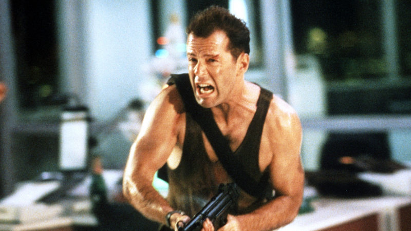   Bruce Willis gritando e correndo com uma arma em Die Hard