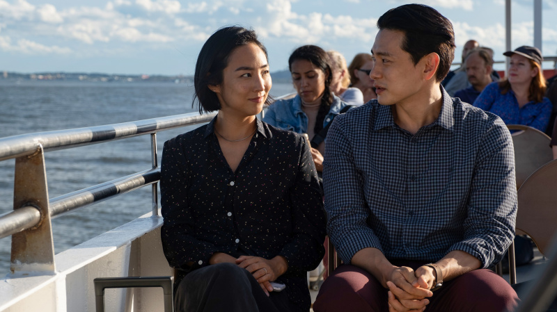 Greta Lee a Teo Yoo sedia na trajekte v minulých životoch