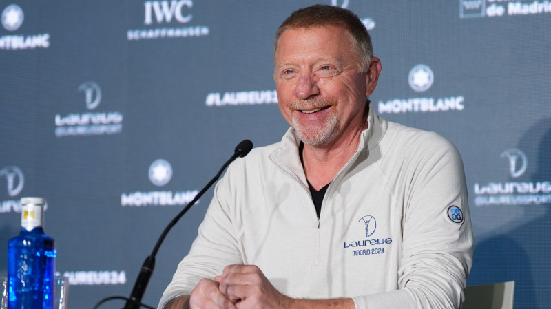   Boris Becker สวมจัมเปอร์สีขาวและพูดใส่ไมโครโฟน