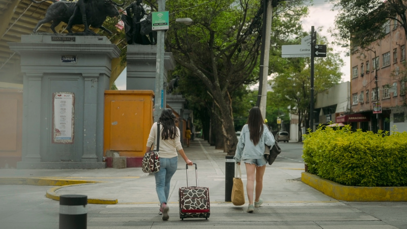   Două femei traversează un drum în Netflix's Caught in the Web: The Murders Behind Zona Divas
