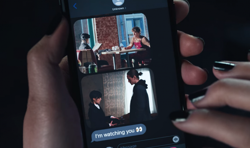   Уензди Адамс' phone screen with a text saying "I'm watching you"