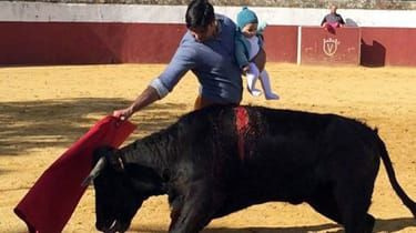 Hiszpański matador walczy z bykiem trzymając swoje dziecko