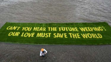 Un banner uriaș crescut pe un covor de iarbă vie le spune guvernelor să „acționeze acum” înainte de COP26, pe 25 iunie 2021
