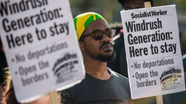 Demonstranci trzymają plakaty podczas protestu wspierającego pokolenie Windrush na Windrush Square w Brixton