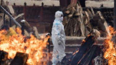 Moški v PPE opazuje, kako gorijo pogrebne grmade