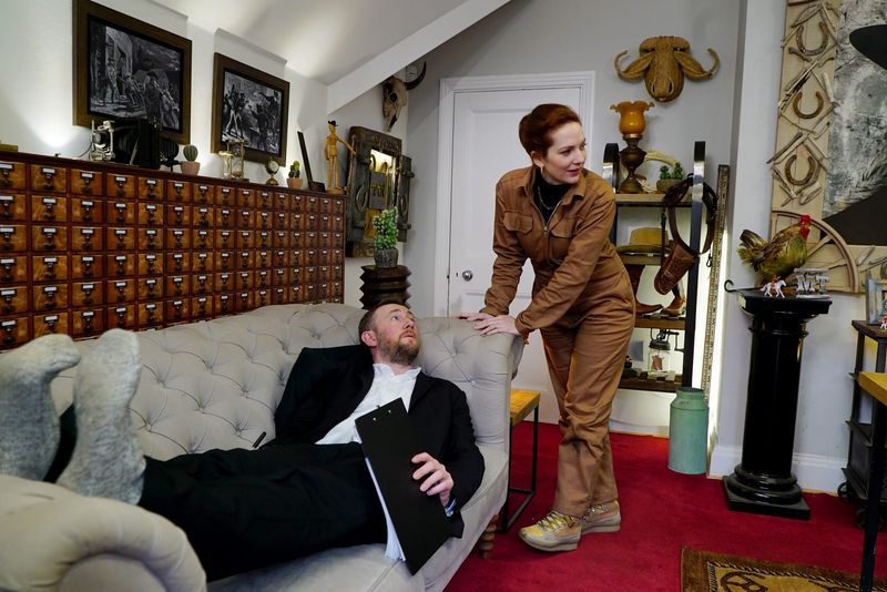 Alex est allongé sur un canapé pendant que Katherine réfléchit à la tâche à accomplir