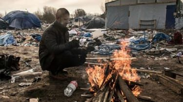 Uchodźca ogrzewa się w obozie dla uchodźców w dżungli w Calais