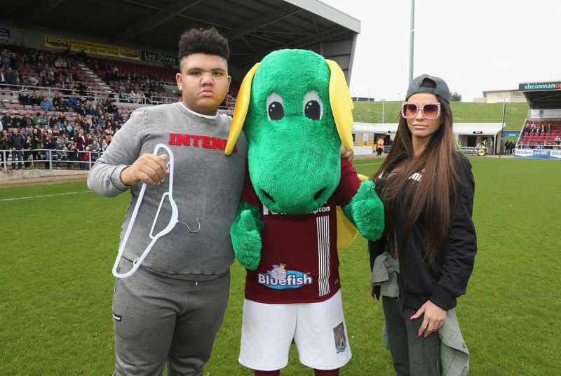 Katy Price y su hijo Harvey posan con la mascota de Northampton Town, Clarence the Dragon, antes de un Celebrity Charity Match en Sixfields el 15 de abril de 2018 en Northampton.