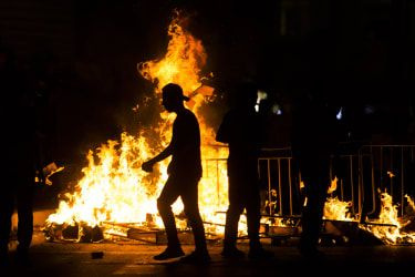 Palestinci stojijo ob goreči barikadi med spopadi z izraelsko policijo