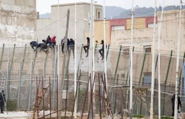 Potencjalni imigranci siedzą na ogrodzeniu granicznym po próbie przedostania się z Maroka do hiszpańskiej enklawy Melilla 10 lutego 2015 r. Ponad 600 imigrantów próbowało dzisiaj wspiąć się na