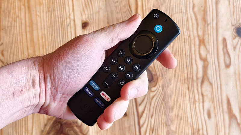   Amazon Fire TV Stick อยู่ในมือเหนือโต๊ะไม้