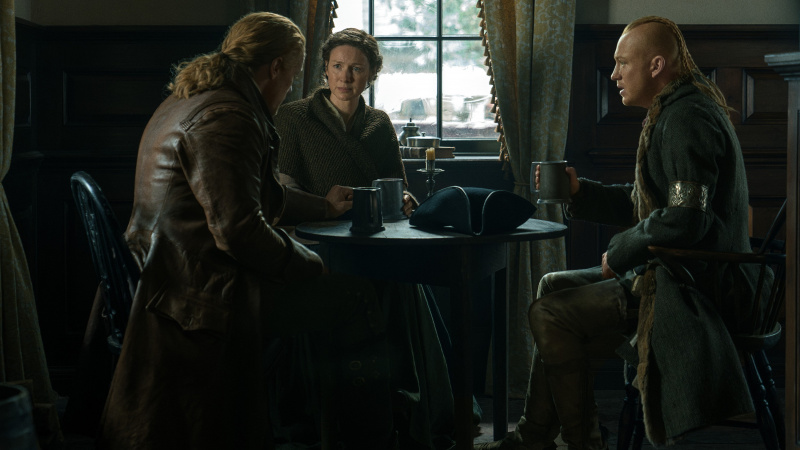   Jamie Fraser, Claire Fraser และ Young Ian นั่งที่โต๊ะในโรงเตี๊ยมใน Outlander Season 7