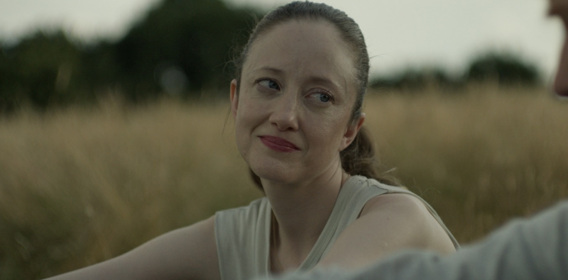   Açık renk bluzlu Andrea Riseborough, Alice ve Jack'teki Alice rolünde tarlada oturuyor