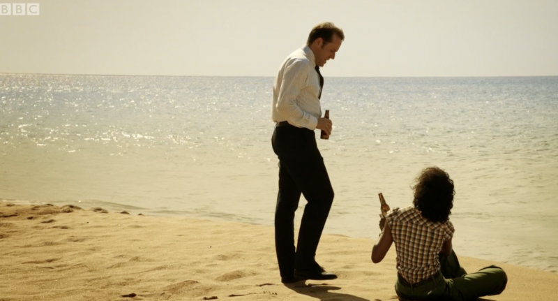   Richard și Camille împart o băutură pe plajă în Death in Paradise sezonul 1 episodul 8