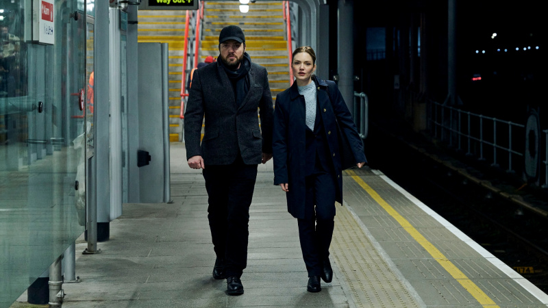   Robin และ Strike เดินบนชานชาลารถไฟใน Strike: The Ink Black Heart