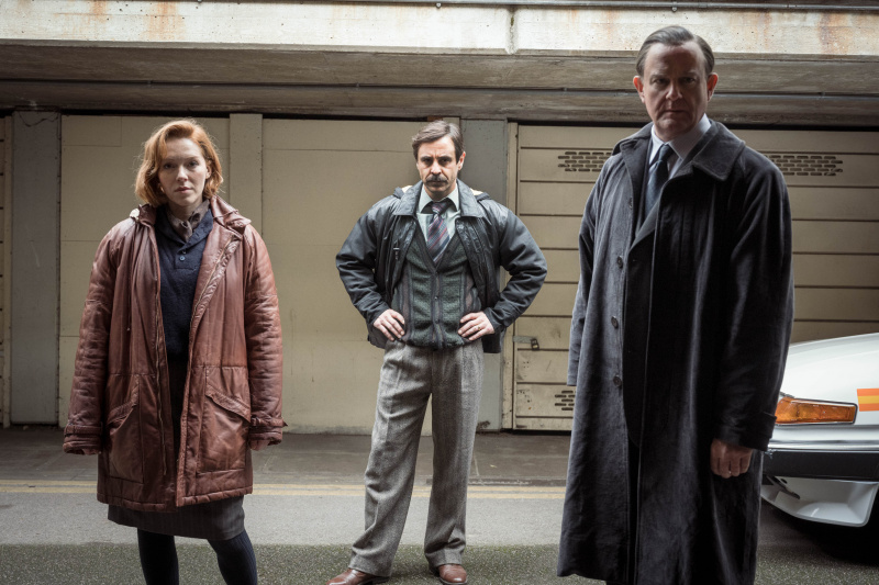   Charlotte Spencer u kestenjastom kaputu kao Nicki Jennings, Emun Elliott u tamnom sakou kao Tony Brightwell i Hugh Bonneville u tamnom kaputu kao Brian Boyce u Zlatu
