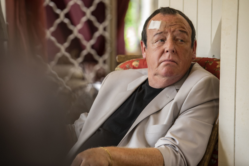  Danny Sheridan (Les Dennis) est assis dans un fauteuil, l'air mal à l'aise, avec un bandage sur le front