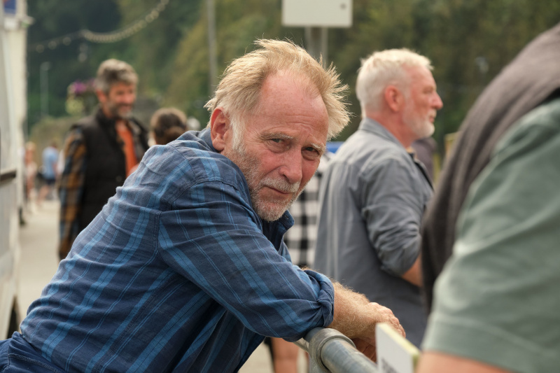   Jaime (Danny Webb) พิงราวจับที่ท่าเรือ โดยหันศีรษะไปด้านข้างแล้วมองเข้าไปในกล้อง