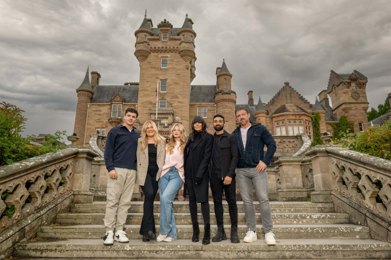   Les finalistes de la série Traitors 2 debout sur les marches à l'extérieur du château avec Claudia Winkleman dans leurs vêtements de tous les jours. De gauche à droite : Harry Clark, Evie Morrison, Mollie Pearce, Claudia Winkleman, Jaz Singh, Andrew Jenkins.