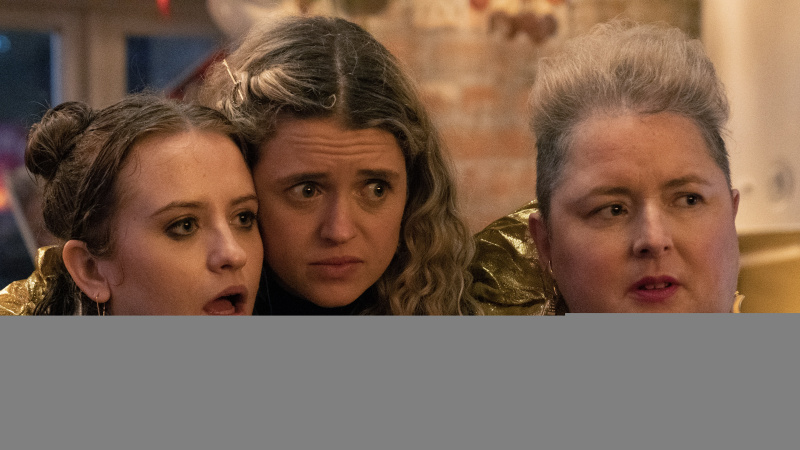   Jen (Máiréad Tyers), Carrie (Sofia Oxenham) a Mary (Siobhán McSweeney), oblečené v párty oblečení, sa k sebe túlia a pozerajú na niečo, čo ich v Mimoriadnom prekvapilo.