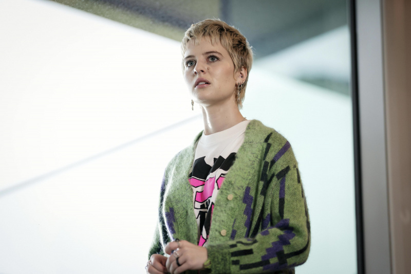  Asher Yasbincek como Hannah em Riptide, em frente a uma grande janela com uma expressão de alarme no rosto