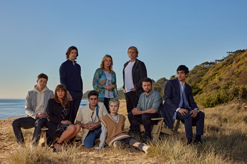  O elenco de Contracorrente reunido em um penhasco gramado com o oceano atrás deles, com Alison (Jo Joyner) no centro