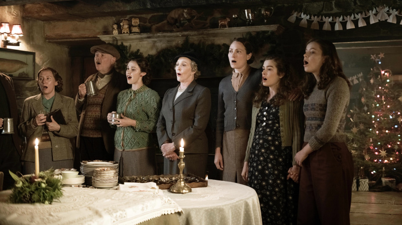   Mevrouw Pumphrey (Patricia Hodge), mevrouw Hall (Anna Madeley), Helen (Rachel Shenton) en Jenny (Imogen Clawson) in oorlogskleding zingen in de pub in All Creatures Great and Small.