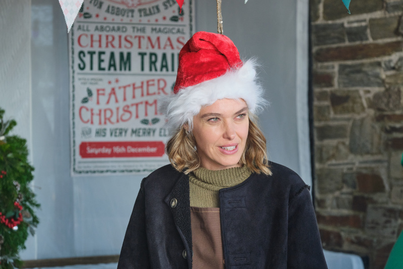  Martha (Sally Bretton) stojí na vianočnom trhu v Shipton Abbott v mikulášskej čiapke