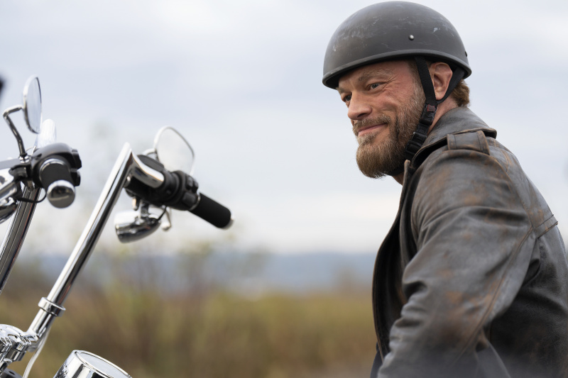  Ares (Adam Copeland) sjedi na motoru (koji je izvan kadra osim upravljača) nosi kacigu i kožnu jaknu i drsko se ceri