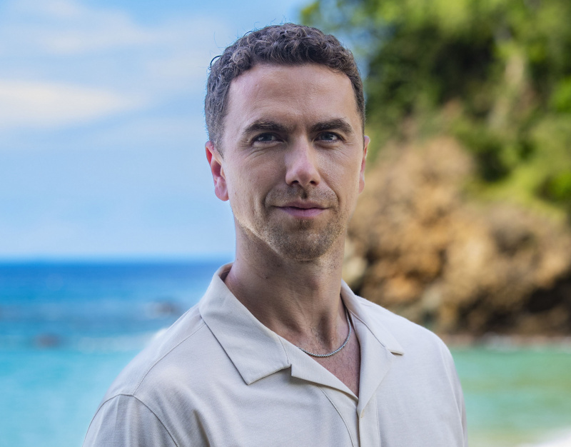   Generička snimka Taylora Fieldinga (Richard Fleeshman) kako stoji na plaži i smiješi se kameri